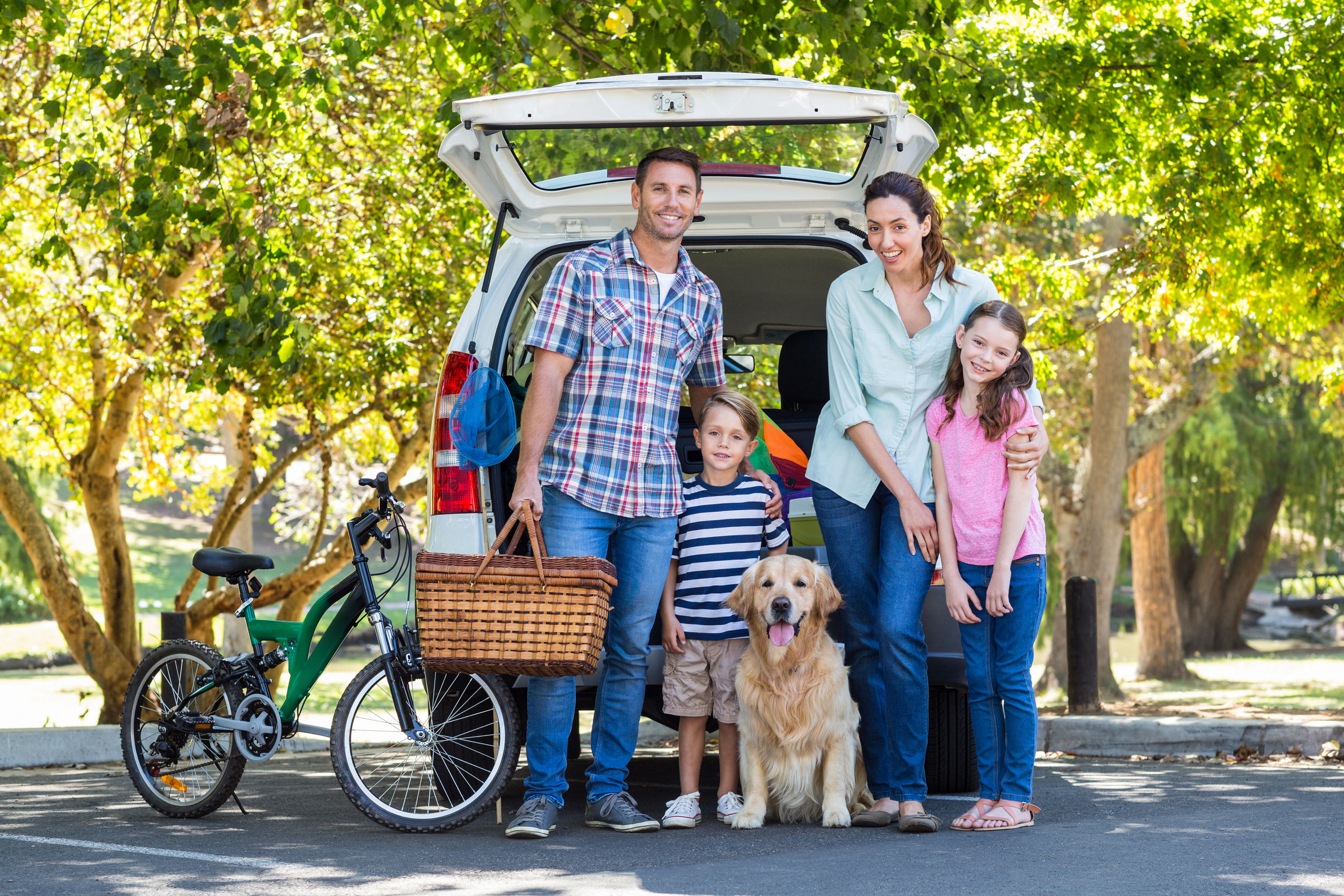 Family and dog standing in front of an SUV with the hatch up