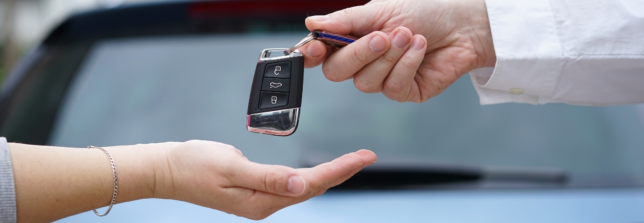 A man handing a set of car keys to a woman featured in a blog post about test drives
